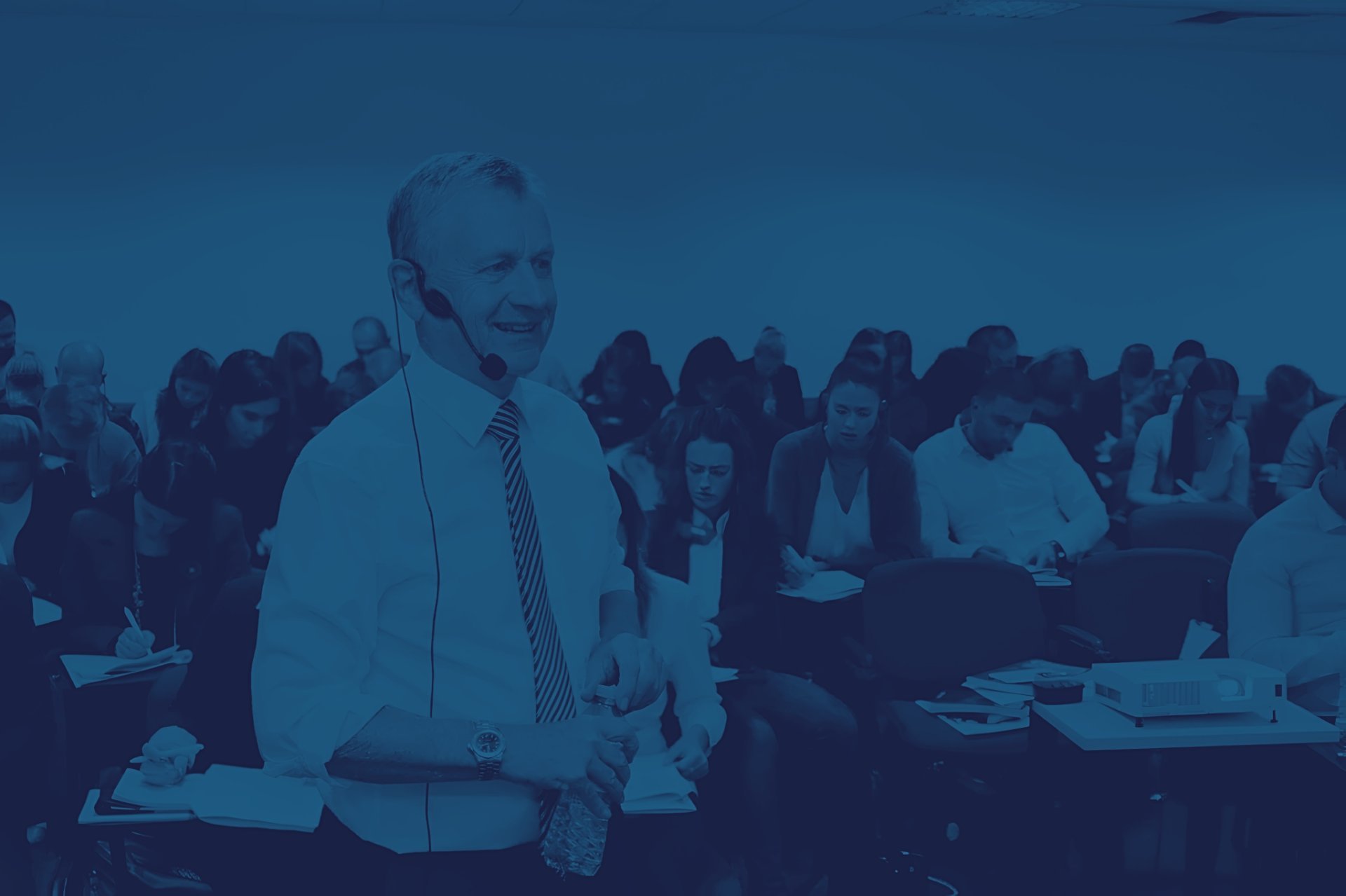 Businessman speaking at podium in front of large audience at corporate event or conference