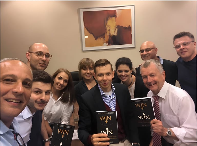 Group of professionals posing together indoors, several holding black books or materials with WIN printed on them